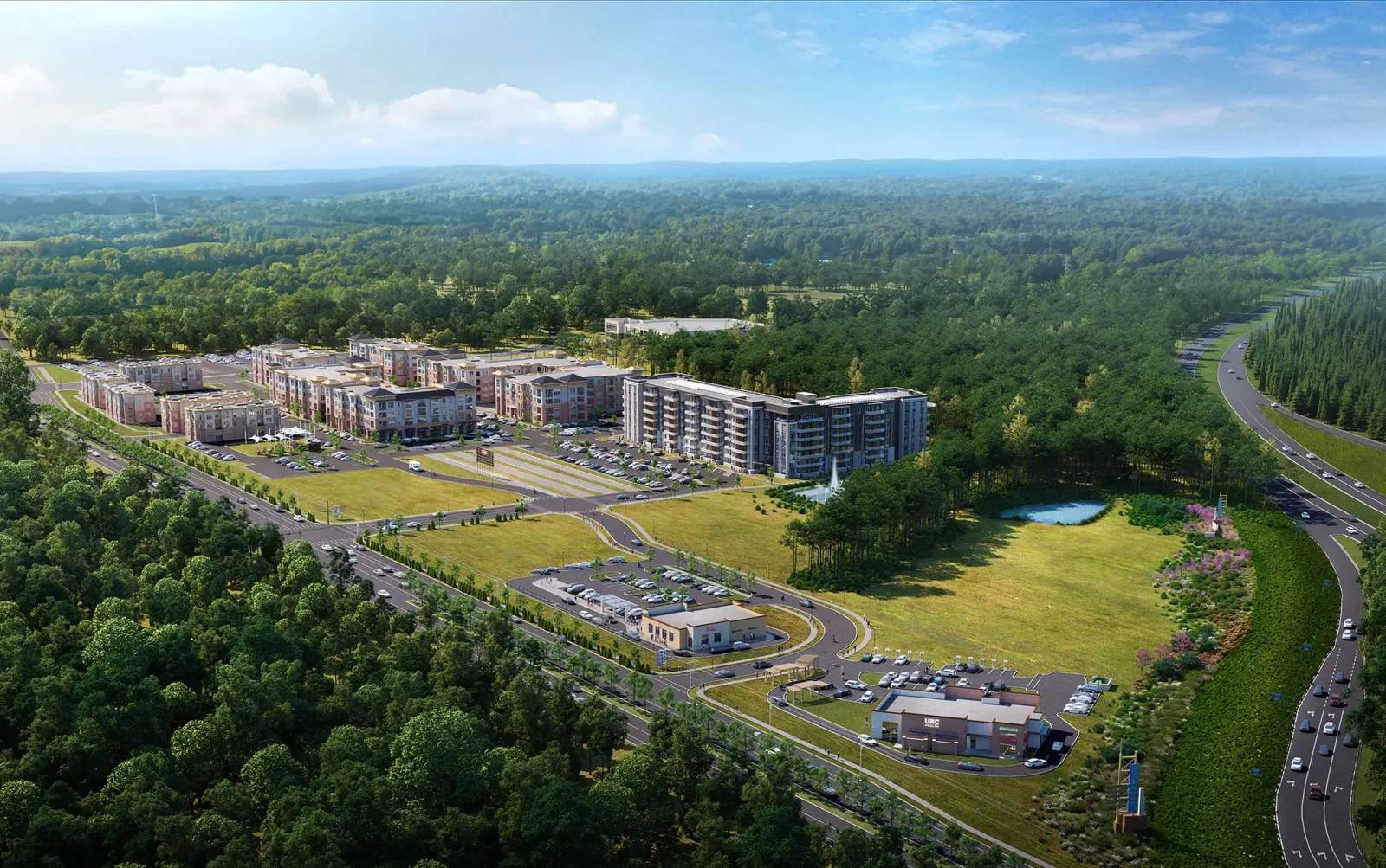 Aerial view of a modern residential complex featuring multiple buildings set amidst greenery. The scene includes a parking lot, roads, and several nearby commercial structures.