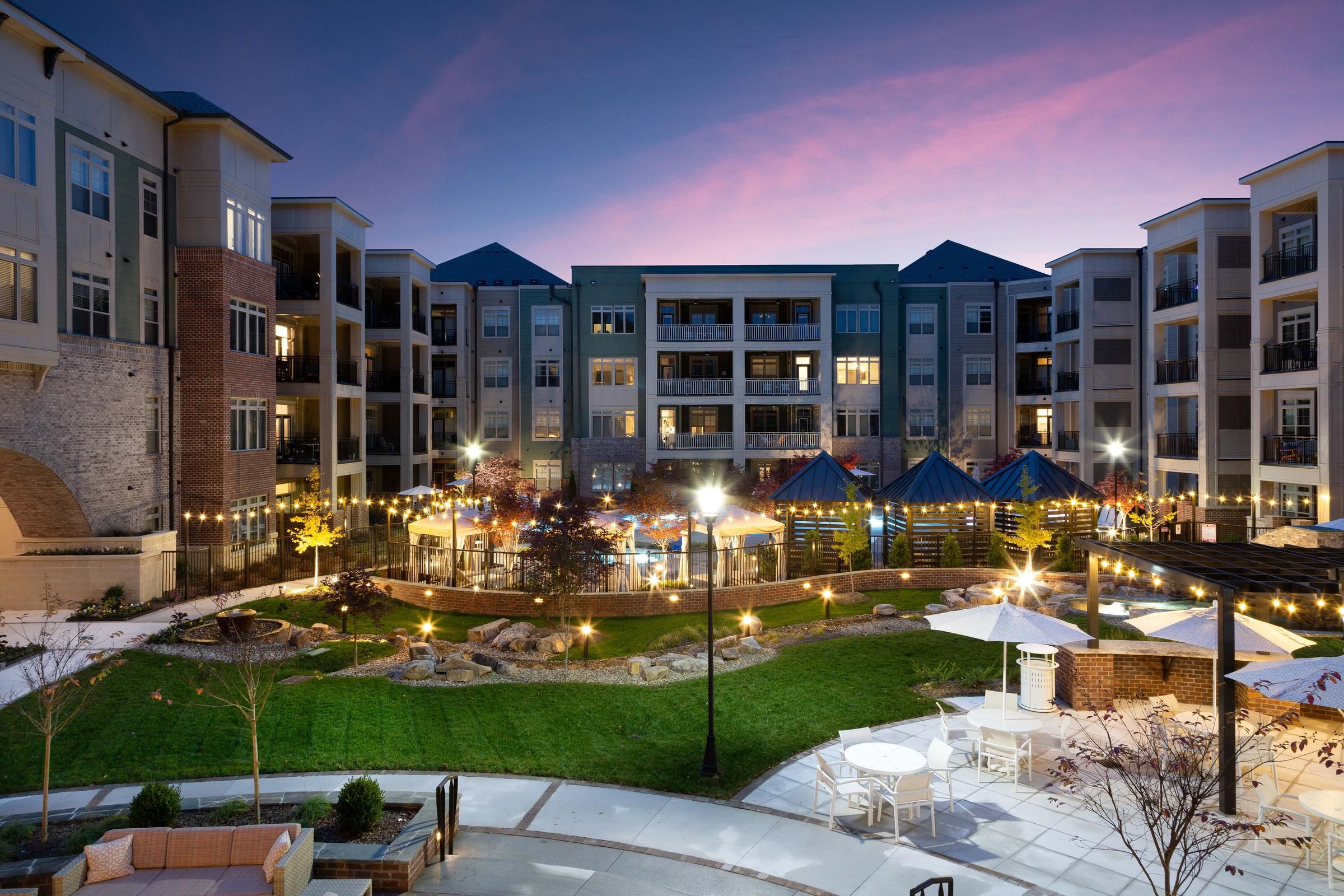 Northwood Ravin Property Management Portfolio, PROVIDENCE ROW in Charlotte, NC, a multi-family, multi-story apartment building exterior with large balconies overlooking a courtyard surrounded by green grass and a pool with cabanas