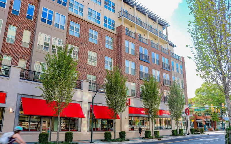 Northwood Ravin Property Management Portfolio, CAROLINA SQUARE in Chapel Hill, NC, a multi-family, multi-story apartment showing the building exterior with plentiful windows and retail shops on the first floor