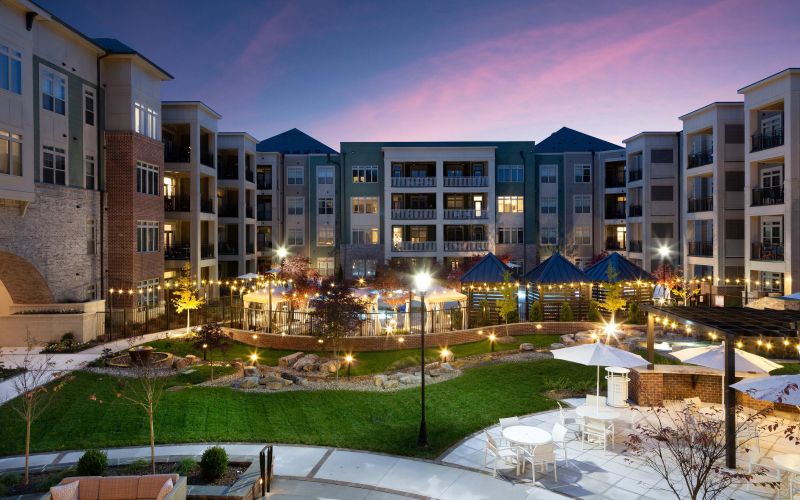 Northwood Ravin Property Management Portfolio, PROVIDENCE ROW in Charlotte, NC, a multi-family, multi-story apartment building exterior with large balconies overlooking a courtyard surrounded by green grass and a pool with cabanas