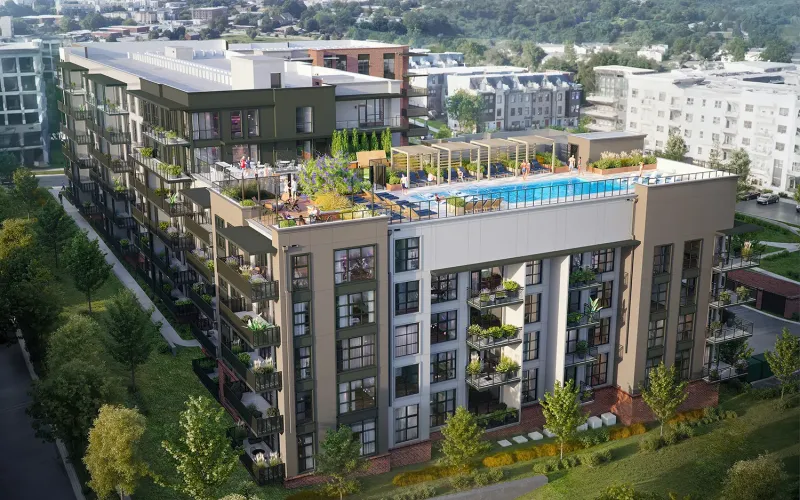 Aerial view of a modern multi-story apartment building with balconies, rooftop garden, and pool. Surrounding the building are greenery, trees, and other residential structures.