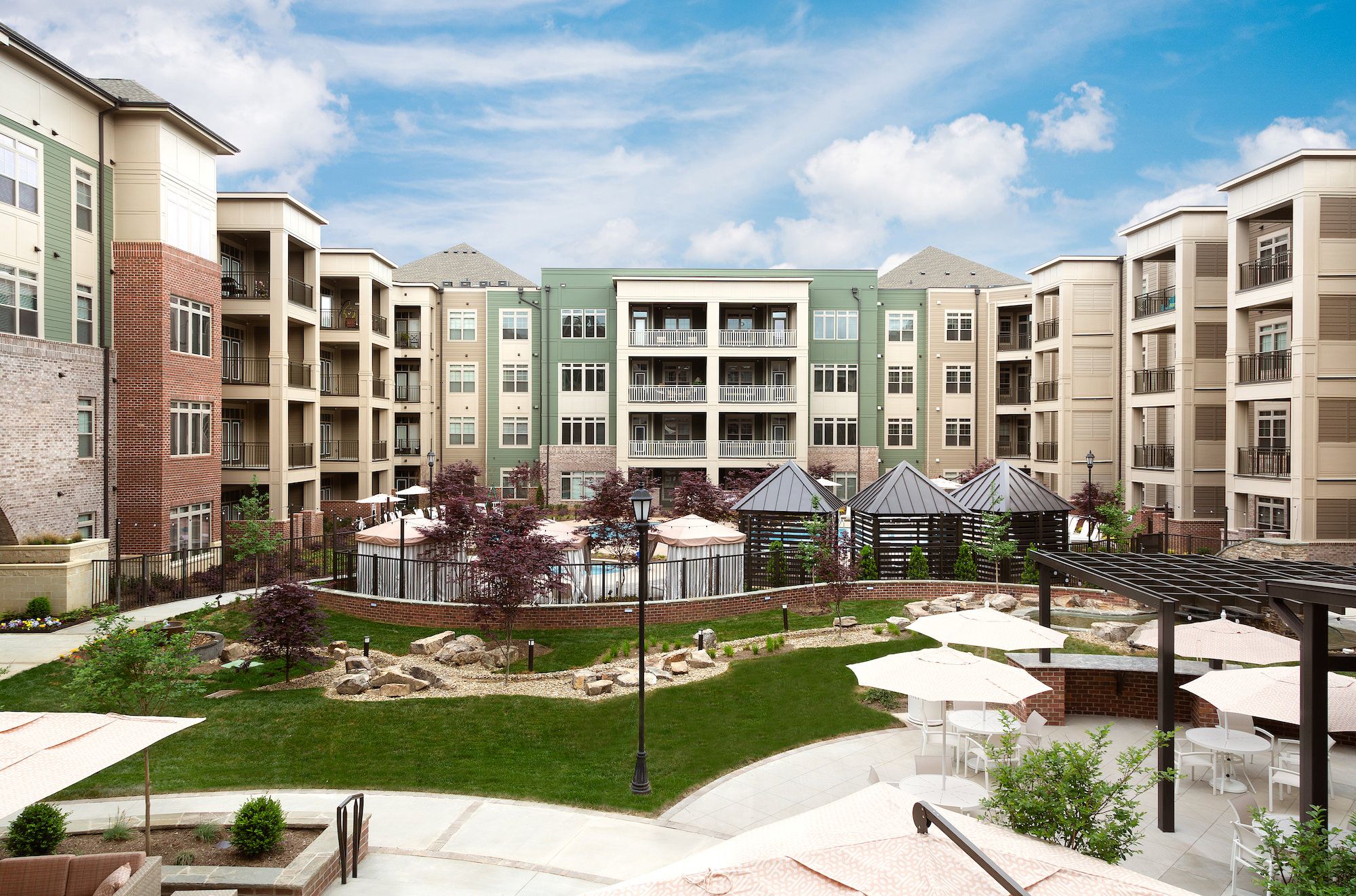Northwood Ravin Property Management Portfolio, PROVIDENCE ROW in Charlotte, NC, a multi-family, multi-story apartment building exterior with large balconies overlooking a courtyard surrounded by green grass and a pool with cabanas